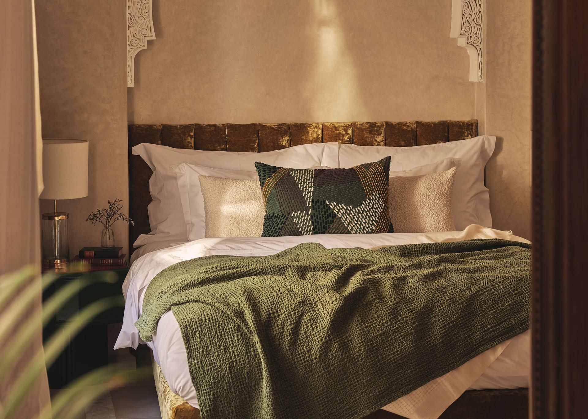 Bed with green throw and golden headboard