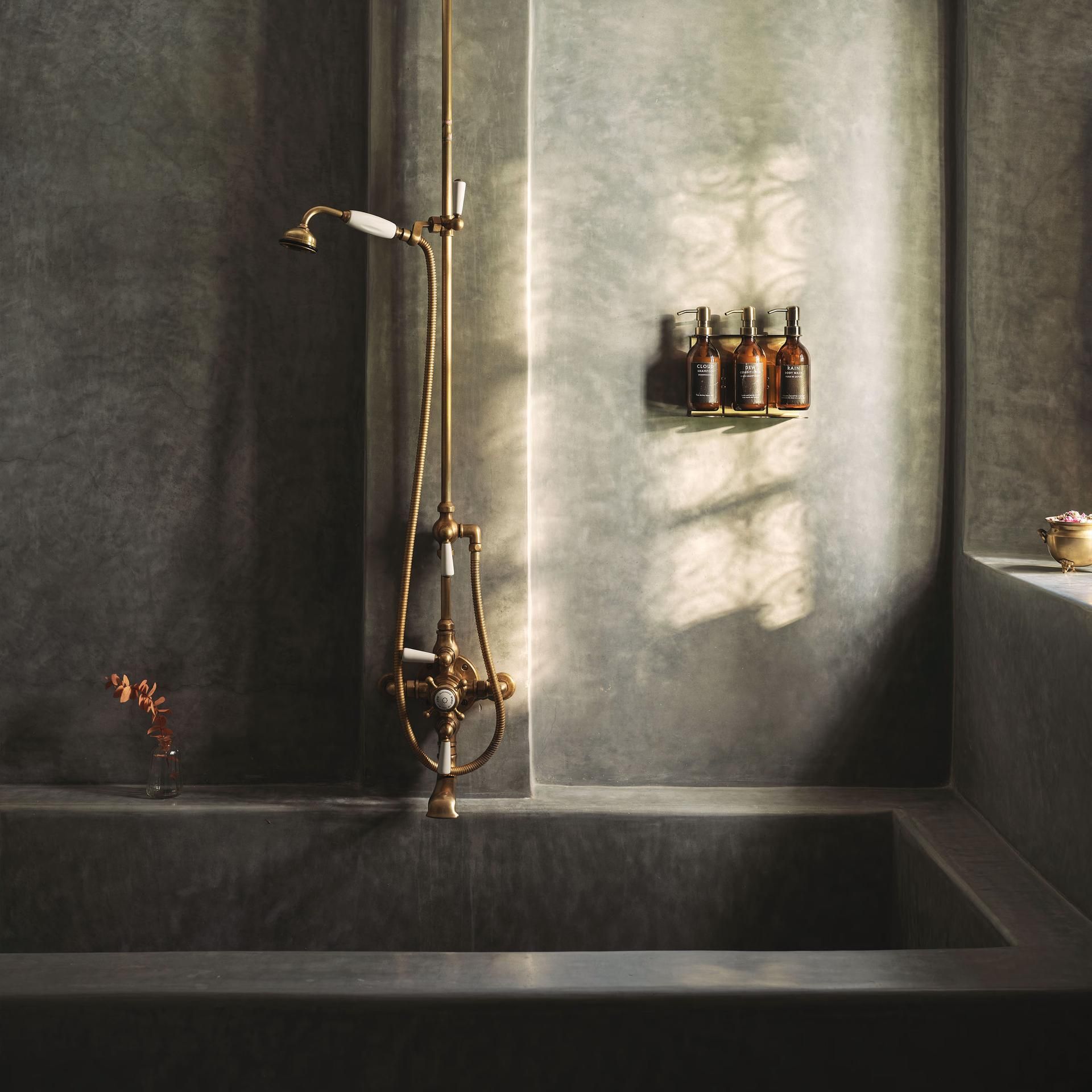 Dark tadelakt bathtub with brass shower