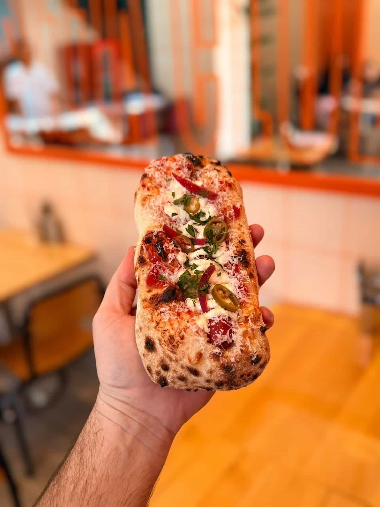A folded slice of pizza held in hand at Pizzaclub